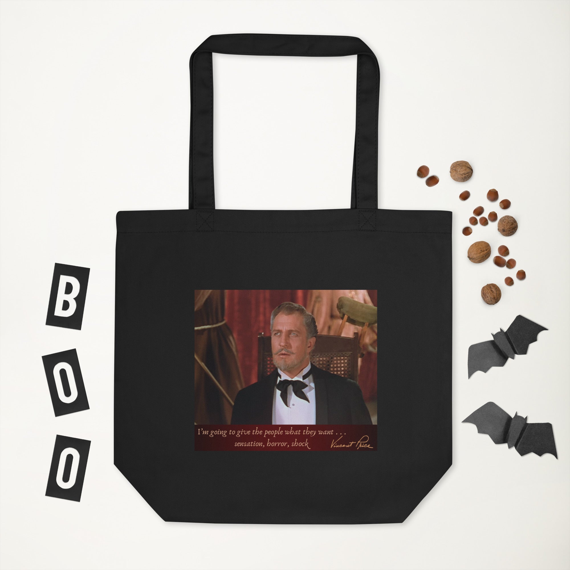 A black organic cotton tote bag featuring a photo of a person in a tuxedo on the front, with 'BOO!' and 'I'm going to kill people' text, accompanied by bats and chocolate pieces around it.