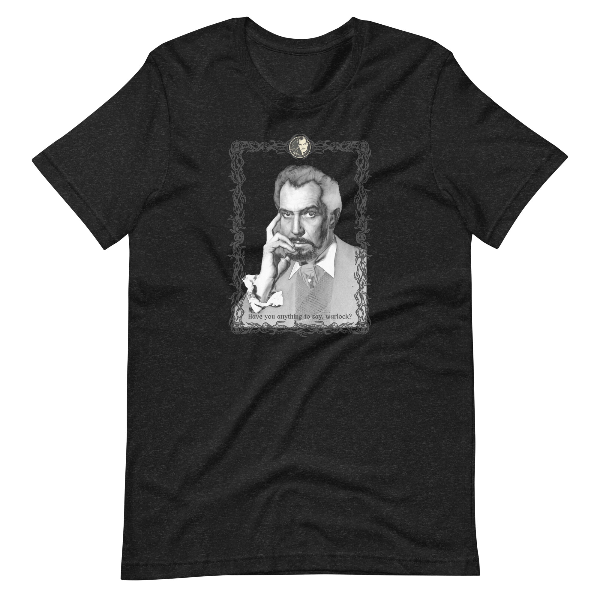 Dark heather black unisex t-shirt laid flat, featuring a black-and-white vintage portrait illustration of a distinguished older man with gray hair resting his hand against his chin, framed in an ornate decorative border with a small cameo medallion at the top. Text at the bottom of the illustration reads: "Have you anything to say, warlock?"
