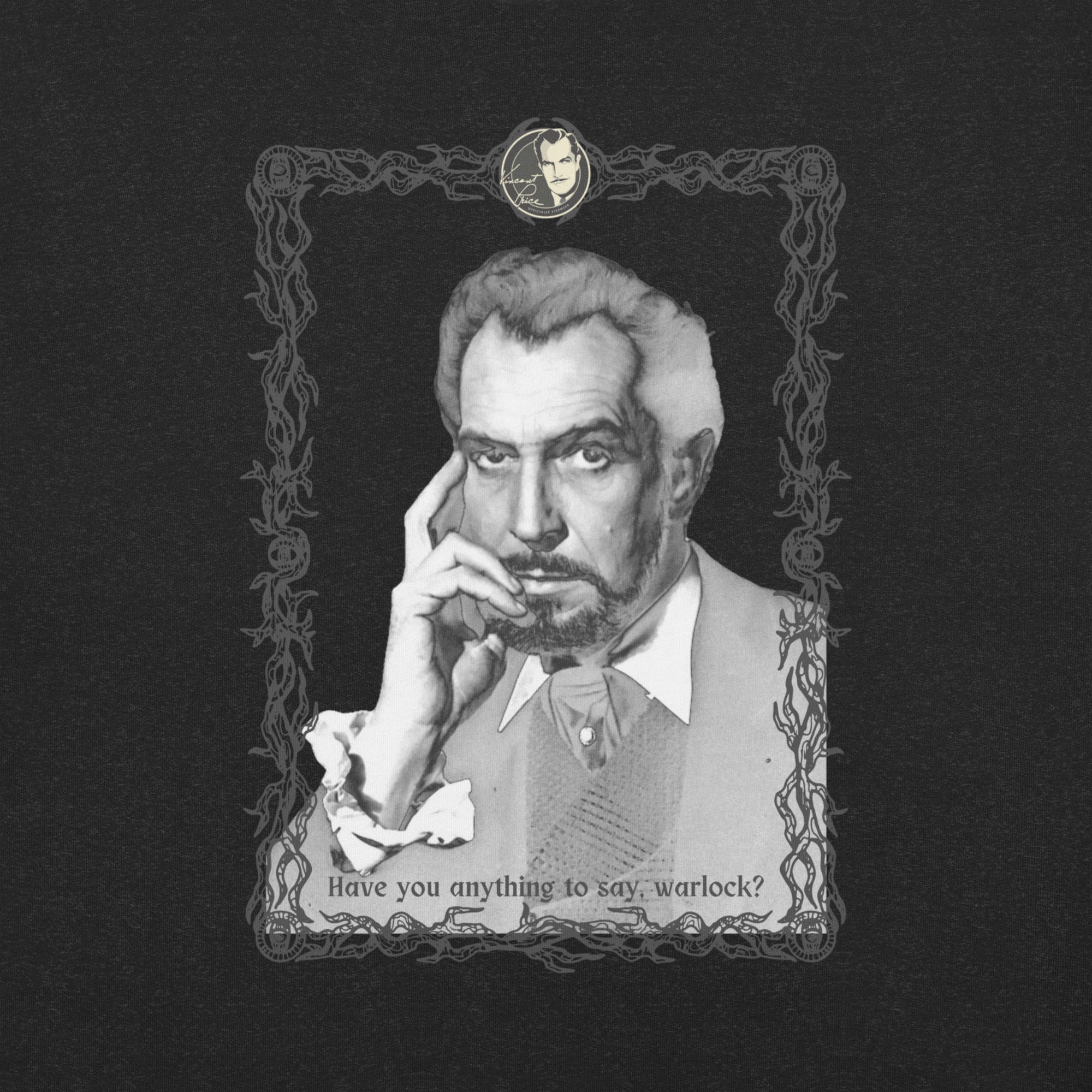 Close-up of the t-shirt graphic on a dark black fabric background: a black-and-white vintage portrait of a distinguished older man with gray hair and a goatee, resting his fingers against his cheek with an intense, brooding expression. He is dressed in a vest and open-collared shirt with ruffled cuffs. The image is framed in an ornate dark border of tangled vines and decorative scrollwork, with a small oval cameo medallion at the top. Text along the bottom reads: "Have you anything to say, warlock?"